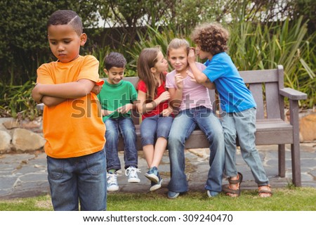 Upset child standing away from group sitting on a bench