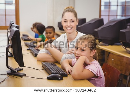 Teacher helping a student using a computer at the elementary school