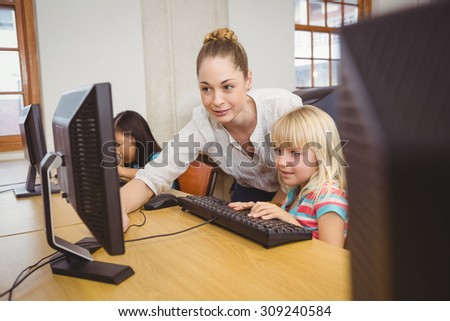 Teacher showing student how to use a computer at the elementary school