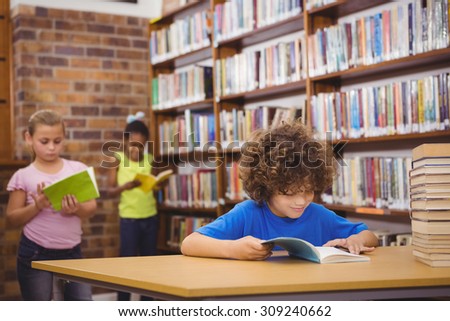 Happy pupil reading a library book at the elementary school