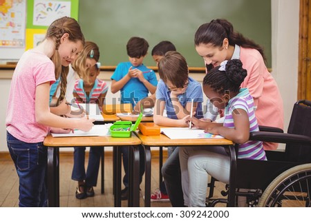 Pupils and teacher working at desk together at the elementary school