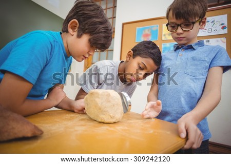Pupils looking at rock with magnifying glass at the elementary school