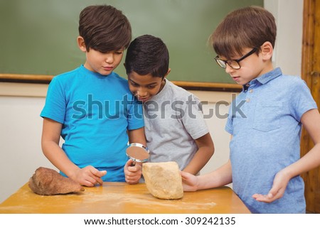 Pupils looking at rock with magnifying glass at the elementary school