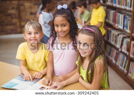 Pupils reading book together in library at the elementary school