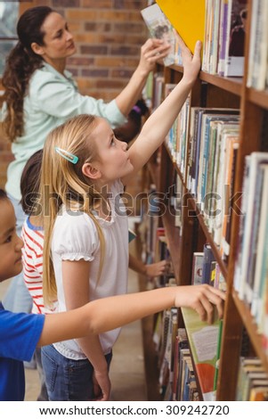 Pupils taking books from shelf in library at the elementary school