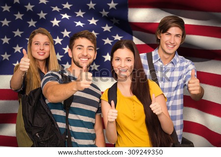 Happy students gesturing thumbs up at college corridor against digitally generated american national flag