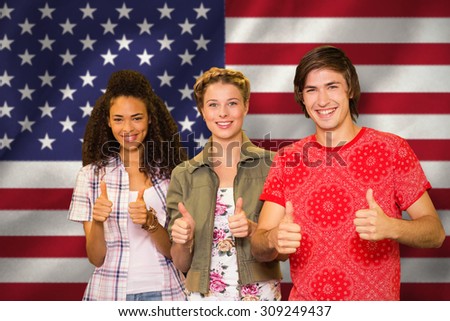 College students gesturing thumbs up in library against digitally generated american national flag
