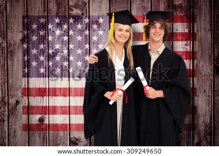 Two students in graduate robe shoulder to shoulder against composite image of usa national flag