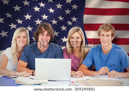 A group of students with a laptop look into the camera against united states of america flag
