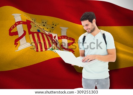 Student using laptop against digitally generated spanish national flag