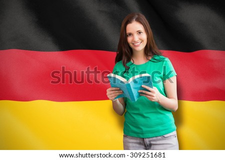Student picking a book from shelf in library against digitally generated german national flag