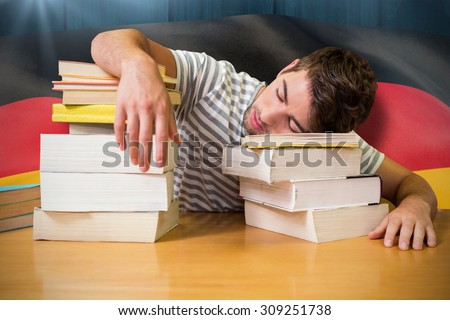 Student asleep in the library against digitally generated german national flag