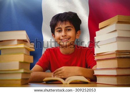 Portrait of boy reading book at desk against digitally generated france national flag