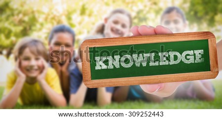 The word knowledge and hand showing chalkboard against happy friends in the park