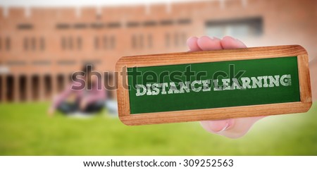 The word distance learning and hand showing chalkboard against students using laptop in lawn against college building