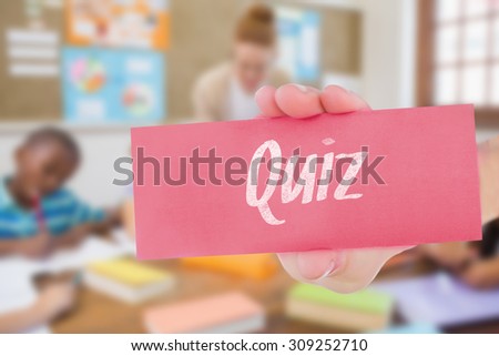 The word quiz and hand showing card against pretty teacher helping pupils in classroom