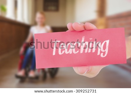 The word teaching and hand showing card against cute pupils writing at desk in library