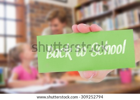 The word back to school and hand showing card against teacher helping pupils in library