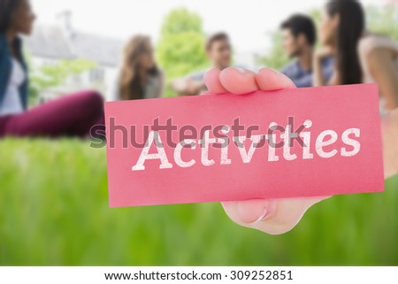 The word activities and hand showing card against happy students sitting outside on campus