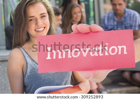 The word innovation and hand showing card against pretty student smiling at camera outside