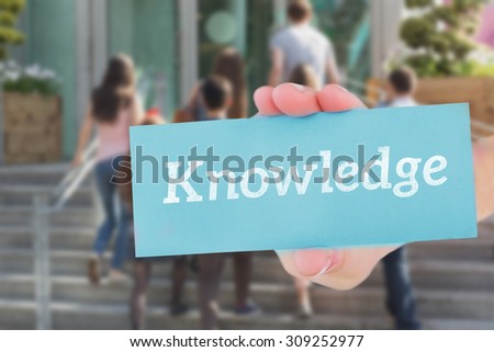 The word knowledge and hand showing card against happy students walking and chatting outside