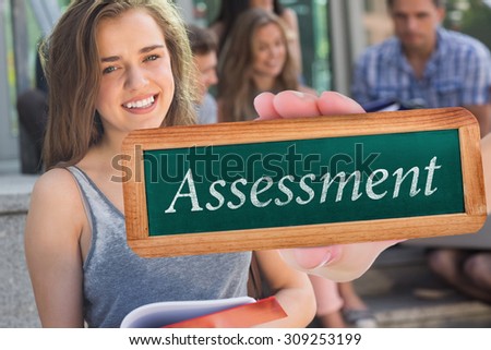 The word assessment and hand showing chalkboard against pretty student smiling at camera outside