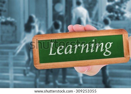 The word learning and hand showing chalkboard against happy students walking and chatting outside