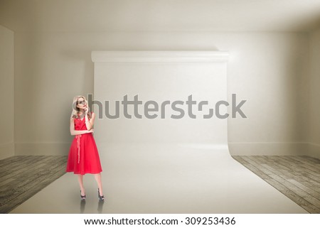 Thoughtful blonde wearing red dress against large white screen