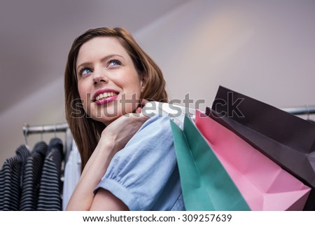 Woman holding shopping bags over shoulder in fashion boutique