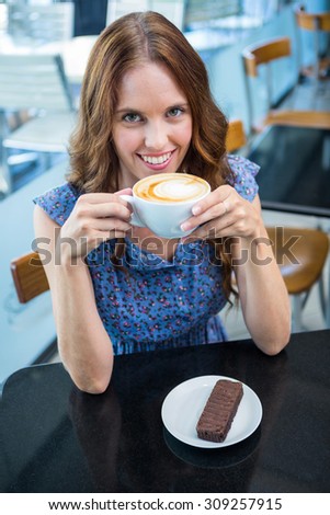 Pretty brunette having coffee and cake in a coffee shop