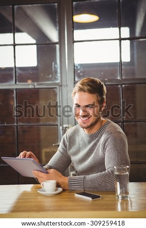 Portrait of handsome man smiling and using tablet computer at coffee shop