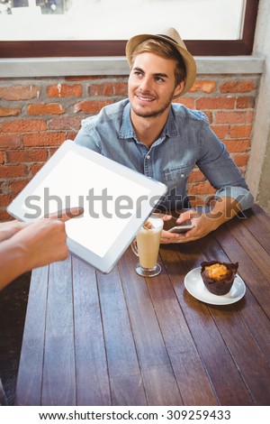Waitress taking handsome hipsters order with tablet at coffee shop