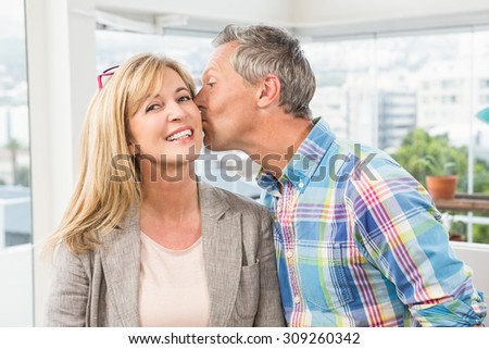 Portrait of casual designer giving his colleague kiss on cheek in the office