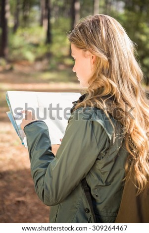 Pretty blonde hiker reading map in the nature