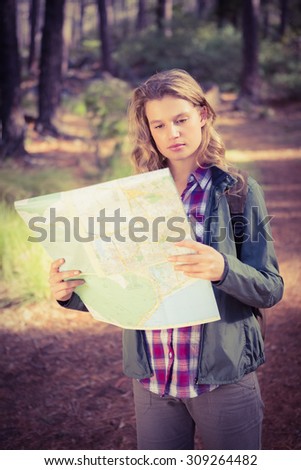 Pretty blonde hiker reading map in the nature