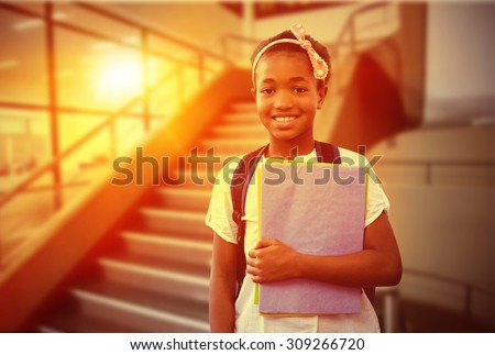 Little girl holding folders in school corridor against empty stair way