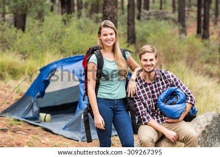 Portrait of a young pretty hiker couple holding a sleeping bag and backpack in the nature