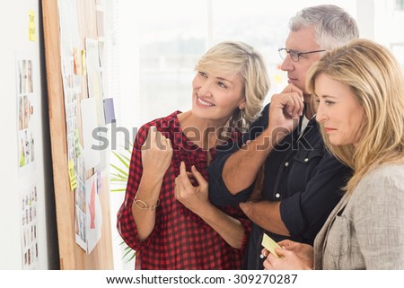 Smiling business team looking at notes on the wall at office
