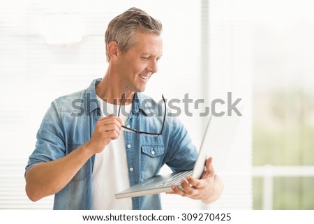 Smiling businessman holding a laptop at the office