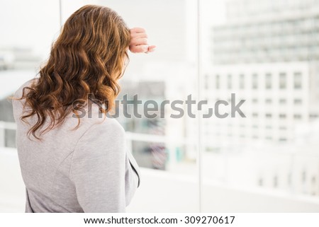 Troubled casual businesswoman leaning against window in the office
