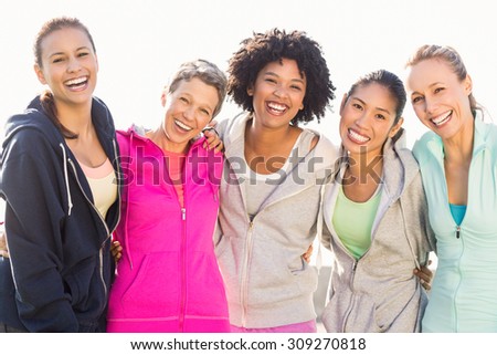Portrait of laughing sporty women with arms around each other in parkland