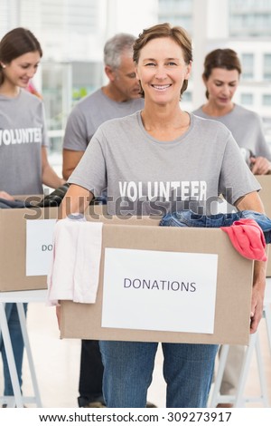Portrait of smiling female volunteer carrying donation box in the office