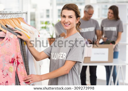 Portrait of smiling female volunteer choosing clothes in the office