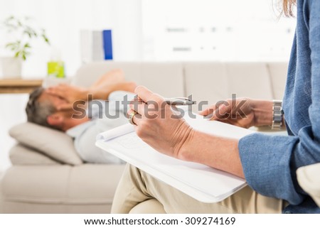 Therapist listening to male patient and taking notes in the office