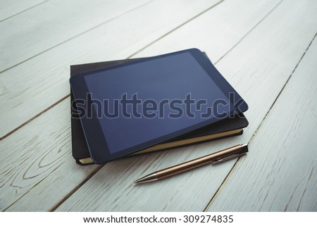 View of a book and tablet lying on desk with pen