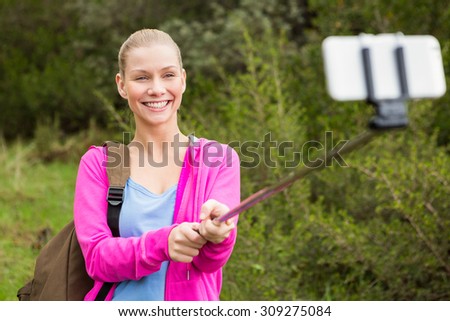 Smiling female hiker taking a selfie with a selfie stick in the nature