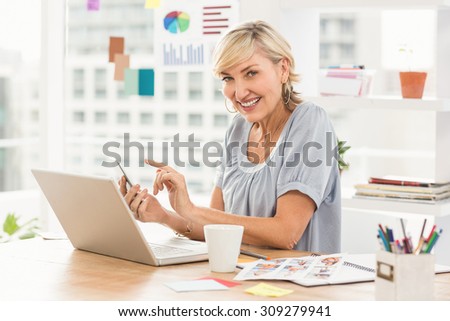 Portrait of a businesswoman using laptop and texting at office
