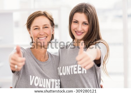 Portrait of smiling female volunteers doing thumbs up in the office