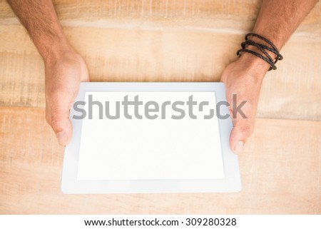 Hands holding blank screen tablet on wooden desk