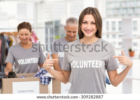 Portrait of smiling female volunteer pointing on shirt in the office